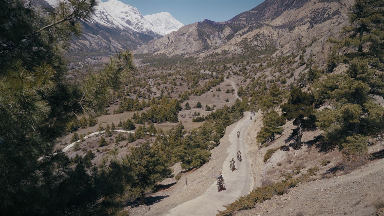 Riders on a winding road through a Himalayan valley